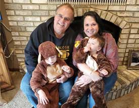 Photo of Wendy's client in home - grandparents holding their grandchildren in sitting in front of fire place