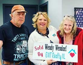 Photo of Wendy Wendorf and her clients while in office and holding sign that says "Sold By Wendy Wendorf"