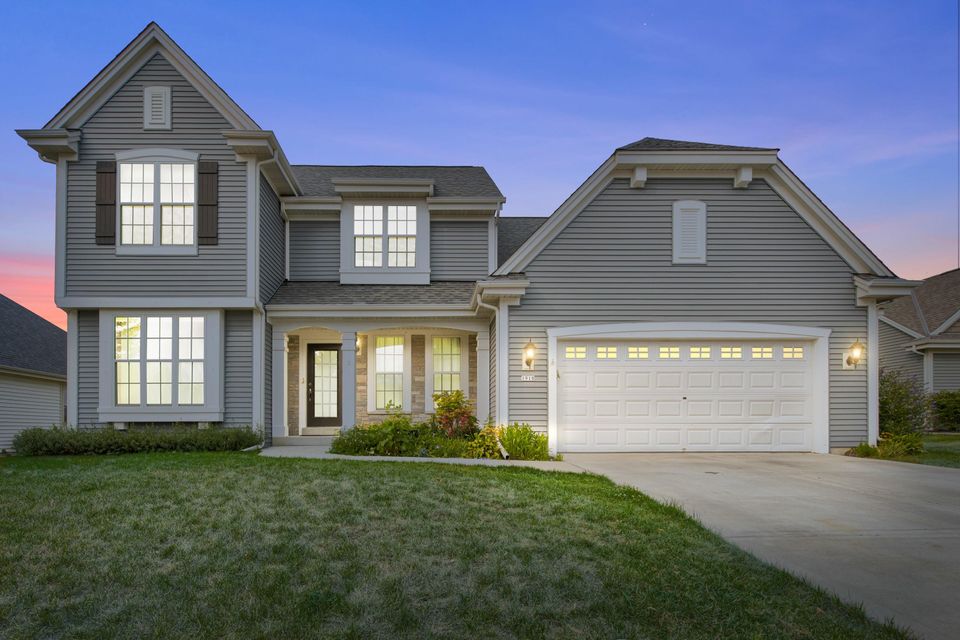 Photo of home with lights on, large garage and big windows