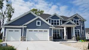Photo of home in daylight, large with 3 car garage, blue exterior and white trim