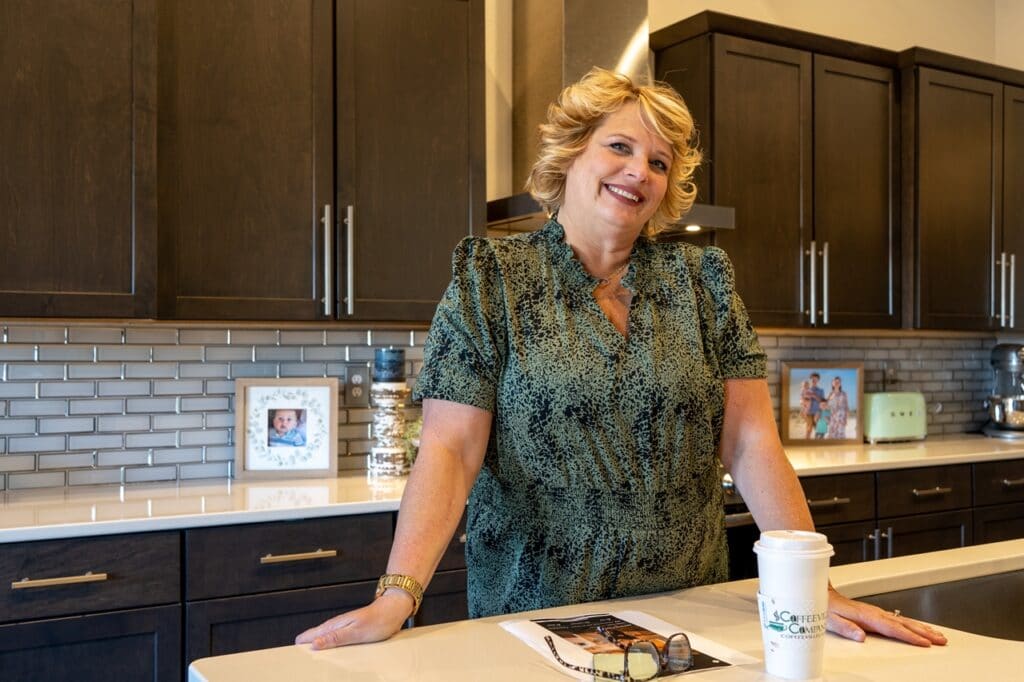 Wendy Wendorf smiling, standing in her kitchen with coffee and glasses on the counter
